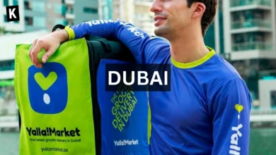 Young man wearing a Yalla Market shirt resting his arm on a Yalla Market delivery bag